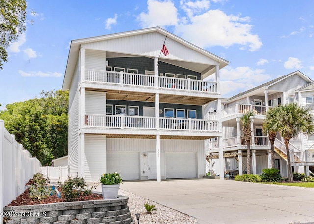 raised beach house featuring fence, an attached garage, and concrete driveway