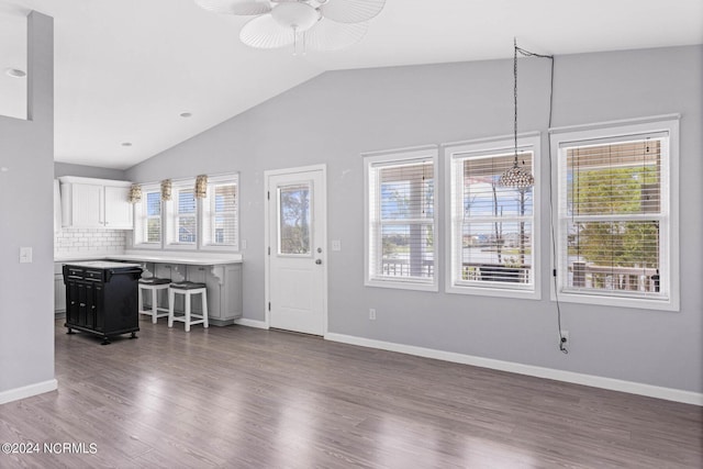 unfurnished living room featuring lofted ceiling, dark wood-type flooring, and baseboards