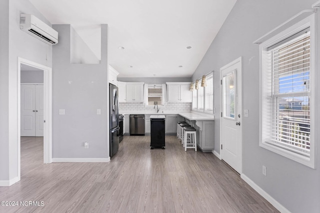 kitchen featuring a breakfast bar, an AC wall unit, stainless steel fridge with ice dispenser, dishwasher, and tasteful backsplash