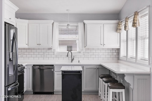 kitchen featuring light countertops, appliances with stainless steel finishes, a sink, and tasteful backsplash