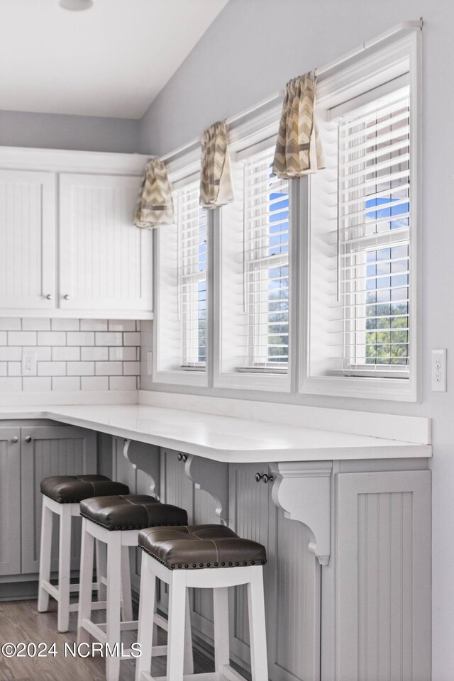 kitchen featuring gray cabinetry, a breakfast bar, dark hardwood / wood-style flooring, and tasteful backsplash