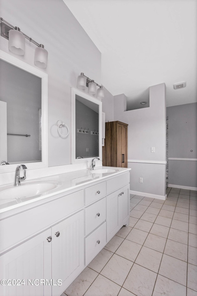 bathroom featuring double vanity, visible vents, a sink, and tile patterned floors