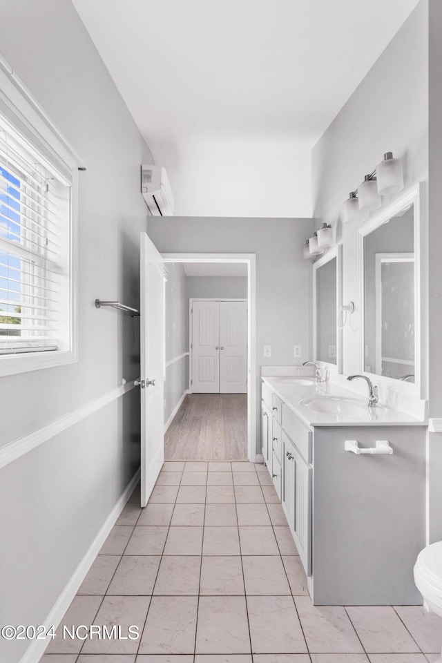 bathroom with an AC wall unit, double vanity, tile patterned flooring, and a sink