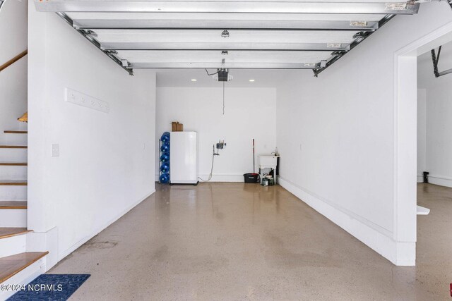 garage featuring sink, white fridge, and a garage door opener