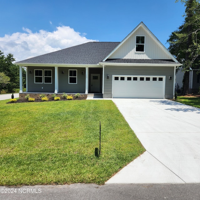 view of front of home with a garage, covered porch, and a front lawn