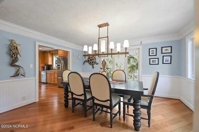 dining area featuring a notable chandelier, light hardwood / wood-style flooring, a textured ceiling, and a wealth of natural light