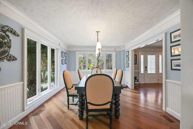 dining area featuring ornamental molding, hardwood / wood-style flooring, and a textured ceiling