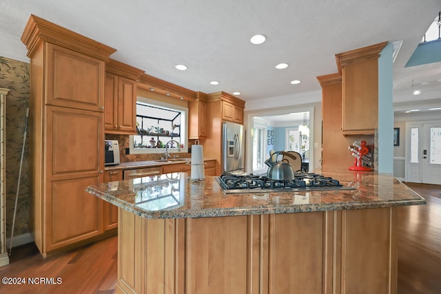 kitchen with dark hardwood / wood-style floors, kitchen peninsula, dark stone countertops, sink, and appliances with stainless steel finishes