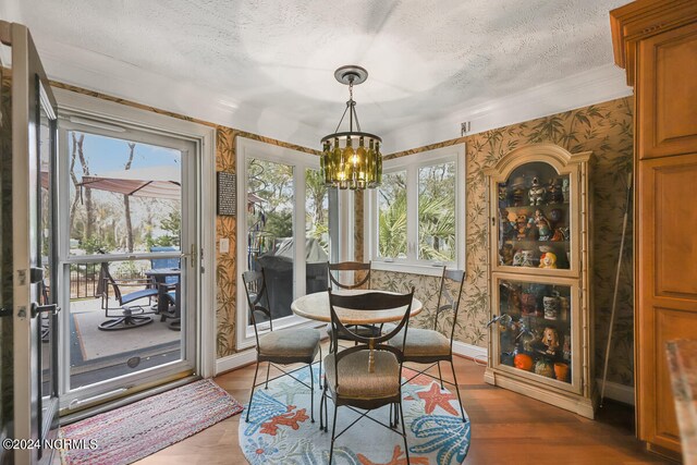 dining area with a textured ceiling, wood-type flooring, and an inviting chandelier