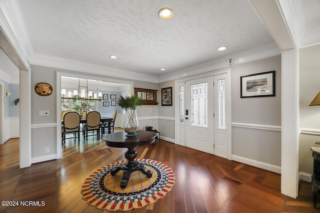 foyer entrance with a textured ceiling, a notable chandelier, dark hardwood / wood-style floors, and crown molding