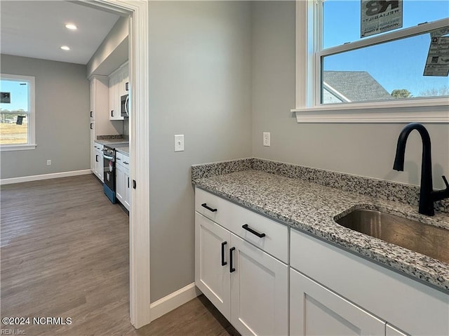 kitchen featuring light stone countertops, dark hardwood / wood-style floors, sink, stainless steel appliances, and white cabinets