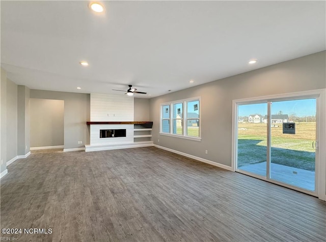 unfurnished living room with dark hardwood / wood-style flooring, ceiling fan, and a fireplace