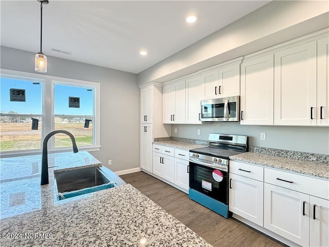 kitchen with sink, light stone counters, appliances with stainless steel finishes, dark wood-type flooring, and white cabinetry