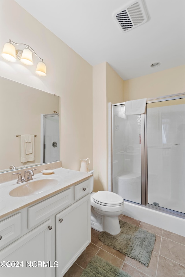 bathroom featuring tile floors, a shower with shower door, large vanity, and toilet