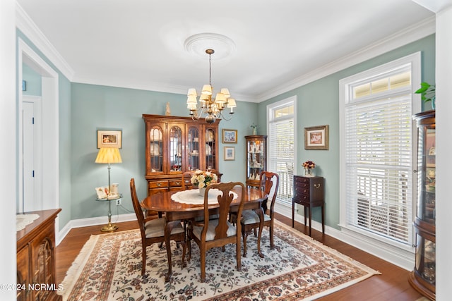 dining space with dark hardwood / wood-style flooring, crown molding, and a chandelier