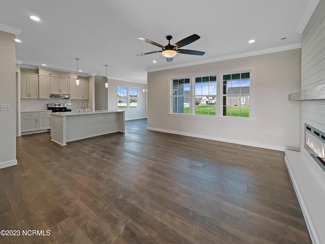 unfurnished living room featuring ceiling fan, a large fireplace, dark wood-type flooring, and crown molding