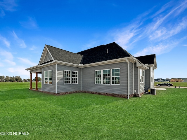 back of property with central AC unit and a lawn