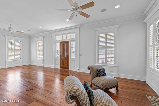 sitting room featuring ceiling fan, ornamental molding, and dark wood-type flooring