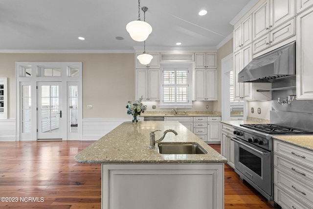 kitchen with an island with sink, decorative light fixtures, dark wood-type flooring, appliances with stainless steel finishes, and sink