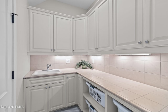 interior space featuring sink, white cabinets, tile floors, tile countertops, and tasteful backsplash