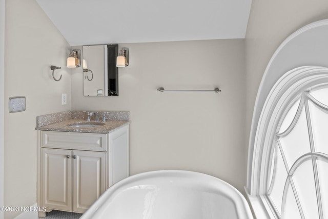 bathroom with oversized vanity, vaulted ceiling, and a bathtub