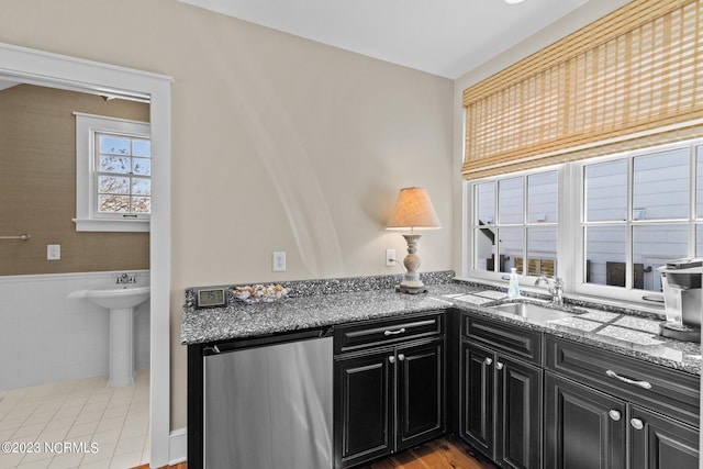 kitchen featuring light tile floors, sink, dishwasher, and stone countertops