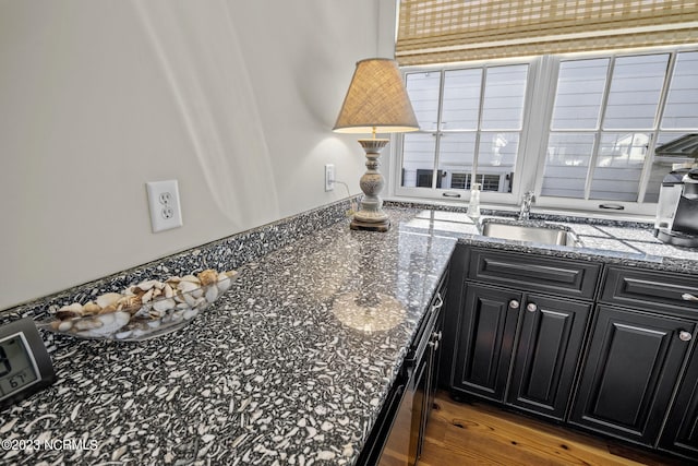 kitchen with dark hardwood / wood-style flooring, sink, and dark stone counters