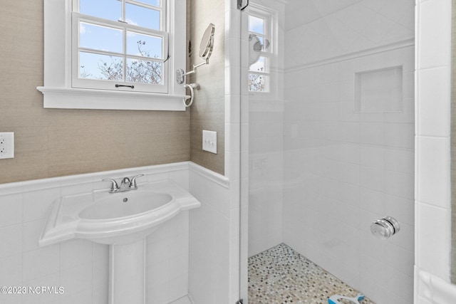 bathroom featuring plenty of natural light, a tile shower, and tile walls