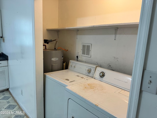 laundry room featuring water heater, light tile flooring, and washer and dryer