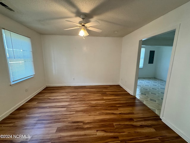 spare room with a textured ceiling, dark hardwood / wood-style floors, ceiling fan, and a wealth of natural light