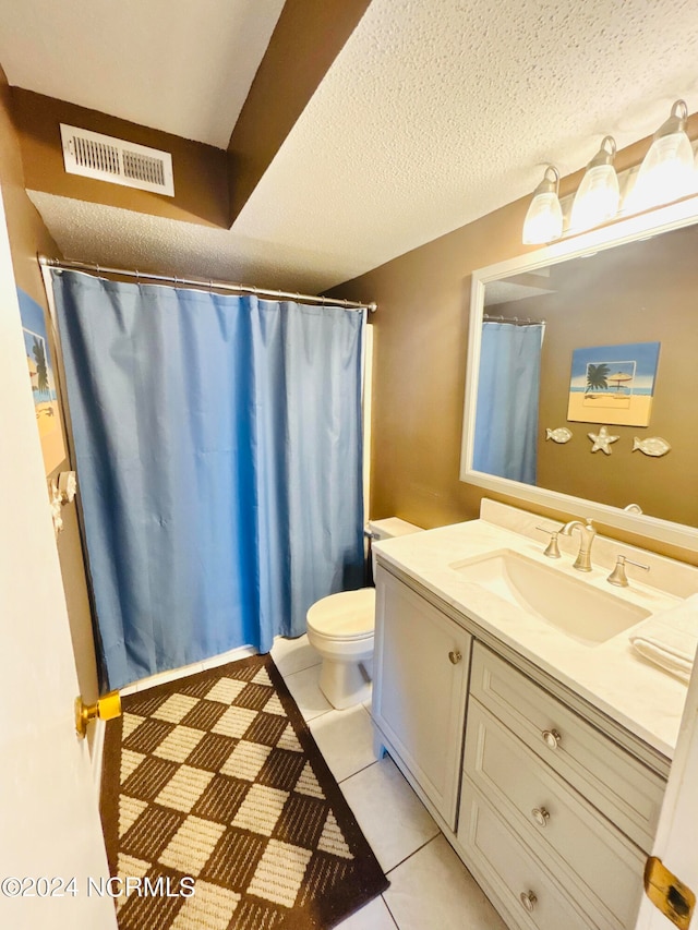 bathroom with toilet, tile floors, vanity, and a textured ceiling