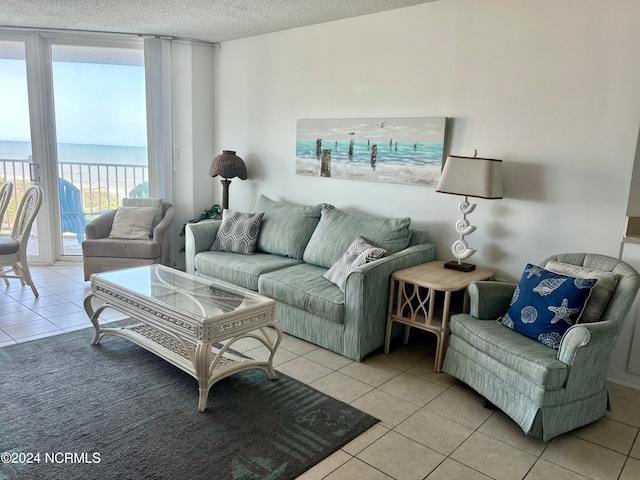 living room with a textured ceiling, light tile floors, and a water view