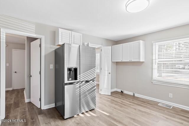 kitchen with white cabinetry, stainless steel refrigerator with ice dispenser, and light wood-type flooring