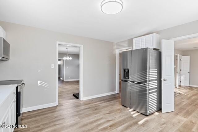 kitchen with a notable chandelier, white cabinets, stainless steel refrigerator with ice dispenser, and light wood-type flooring