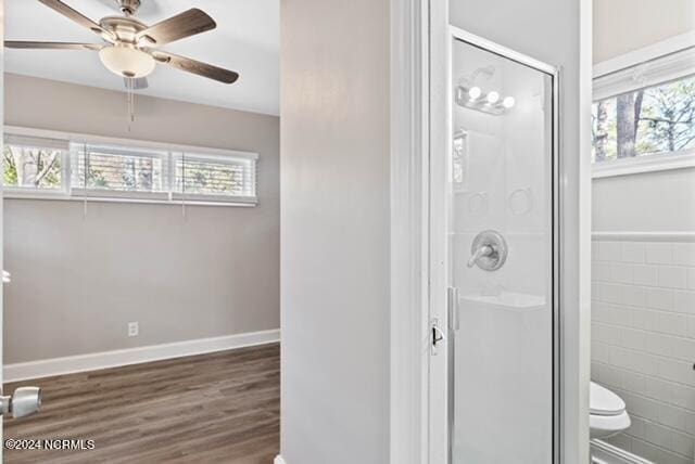 bathroom with toilet, wood-type flooring, a wealth of natural light, and tile walls