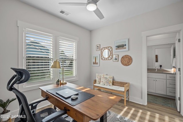 office area with ceiling fan, light hardwood / wood-style flooring, and sink