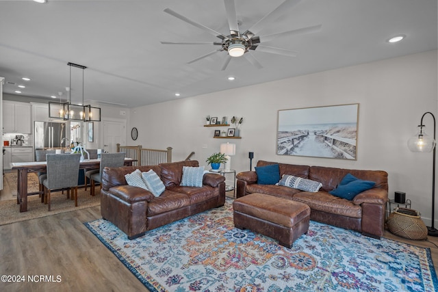 living room featuring ceiling fan with notable chandelier and light wood-type flooring