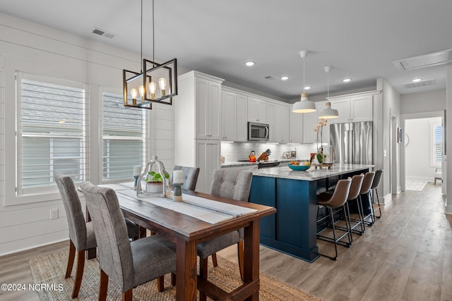 dining space with a chandelier and light hardwood / wood-style flooring