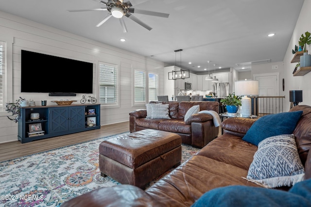 living room featuring hardwood / wood-style flooring and ceiling fan with notable chandelier