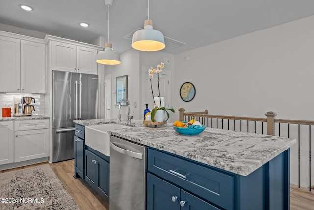 kitchen featuring pendant lighting, a center island, appliances with stainless steel finishes, white cabinets, and backsplash