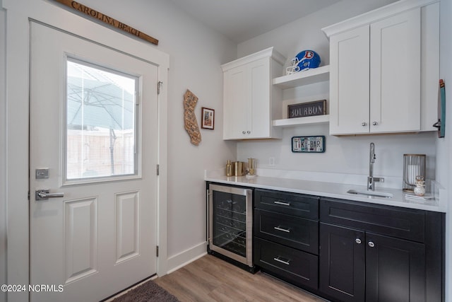 kitchen featuring wine cooler, white cabinetry, sink, and light hardwood / wood-style flooring