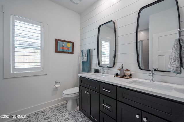 bathroom featuring tile floors, dual sinks, vanity with extensive cabinet space, and toilet