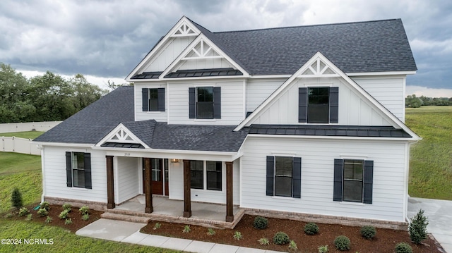 view of front of house featuring metal roof, a patio, a shingled roof, board and batten siding, and a standing seam roof