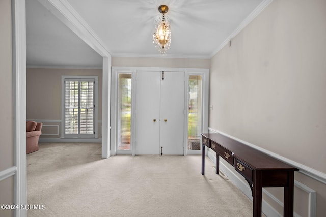 carpeted entrance foyer with ornamental molding and a chandelier