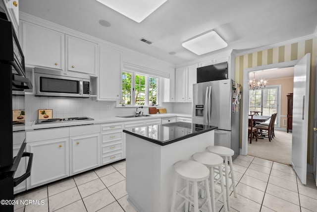 kitchen featuring white cabinets, a chandelier, stainless steel appliances, and a center island