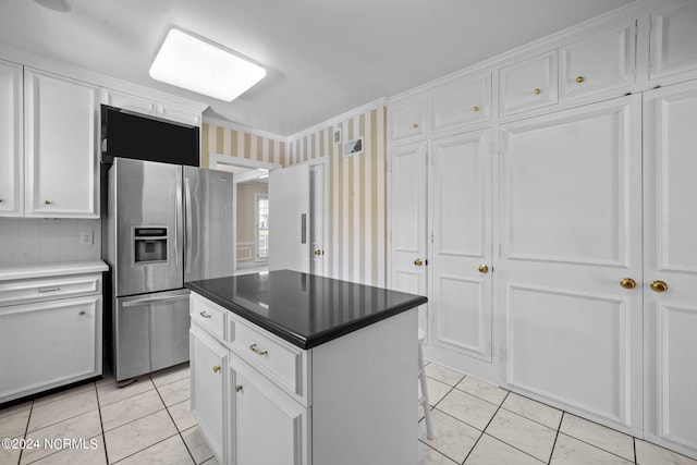 kitchen featuring a center island, stainless steel fridge, light tile floors, white cabinetry, and ornamental molding