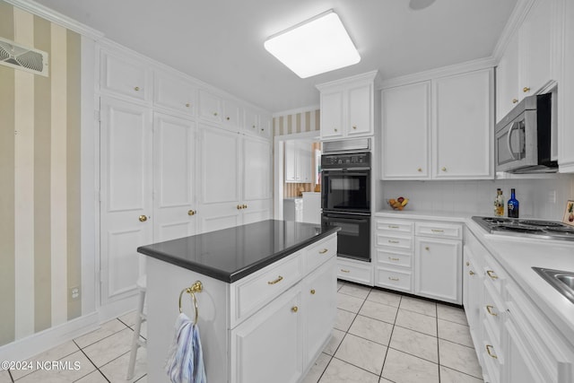 kitchen featuring a kitchen island, stainless steel appliances, light tile flooring, and white cabinetry