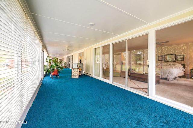 unfurnished sunroom featuring a baseboard radiator and ceiling fan