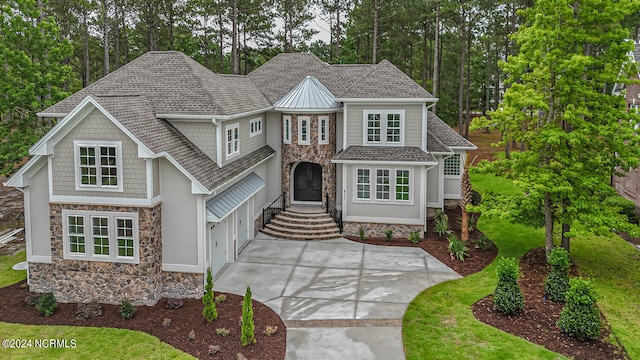 view of front of home featuring stone siding, roof with shingles, and driveway