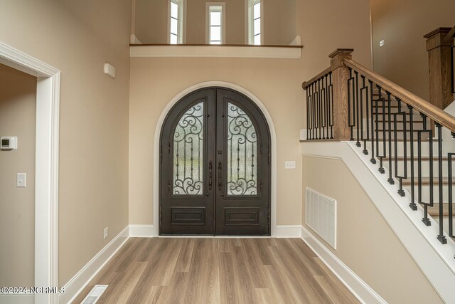 entrance foyer with a high ceiling, hardwood / wood-style floors, and french doors